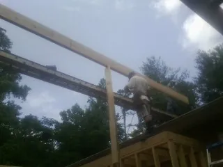 Carpenter setting a ridge beam over a new addition frame — Ice Dam Removal by Roofing Brothers in Rayland