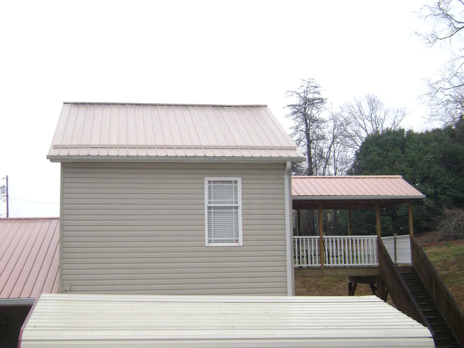 Tan metal roofs on a two story addition and attached porch, from a Roof Replacement job in Rayland