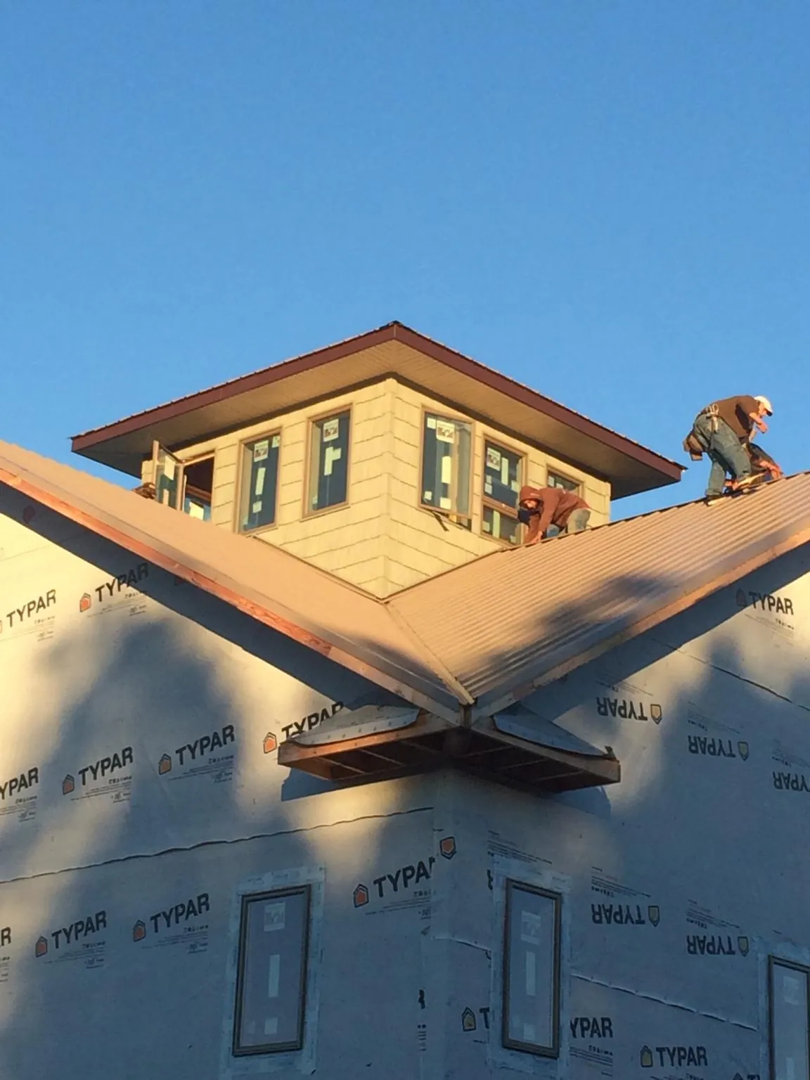 Roofers working around a rooftop cupola on a new metal roof at sunset — Roof Waterproofing in Rayland by Roofing Brothers